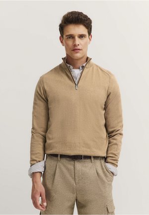 Beige quarter-zip pullover with a textured fabric, featuring a collar over a striped shirt. Slim fit, long sleeves, minimal accents.
