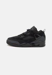 Black sneakers with a textured suede upper, mesh panels, and a patterned rubber sole. Features black laces and branding on the tongue.