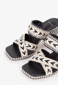 Sandali neri open-toe con forma quadrata, intrecciati in fibre naturali con accenti bianchi e beige, cinturini testurizzati e bordi decorativi.
