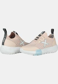 Zapatillas deportivas de color rosa claro con parte superior de malla, suela de amortiguación blanca y acentos en gris y azul claro en contraste, con une pestaña de tirón en el talón.