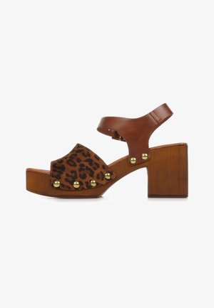 Sandalo platform marrone con tacco largo, fascia frontale con stampa leopardata e borchie dorate, e cinturino marrone alla caviglia con chiusura a fibbia.