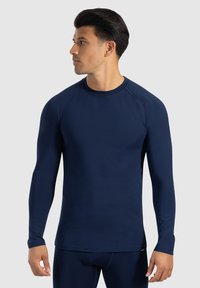 Maglietta atletica a maniche lunghe di colore blu navy con scollatura a girocollo, texture liscia e maniche raglan. Progettata per il massimo comfort durante le attività fisiche.