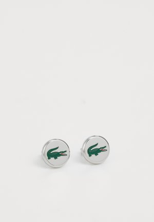 Cufflinks rotondi in argento con un logo di coccodrillo verde e dettagli rossi, superficie lucida e texture liscia.