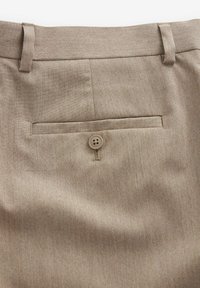 Beige broeken van textuurstof met een achterzak en knoopsluiting, voorzien van riemlussen en een gladde afwerking.