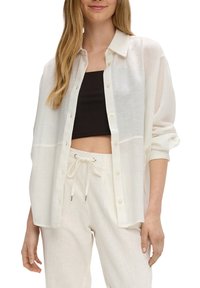 Lättviktig vit skjorta med avslappnad passform, med krage och lätt genomskinlighet. Matchad med off-white byxor.