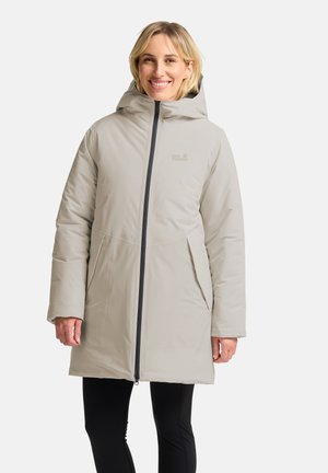 Cappotto beige a lunghezza ginocchio con zip frontale e cappuccio, caratterizzato da una texture liscia e tasche laterali. Accenti neri lungo la zip.