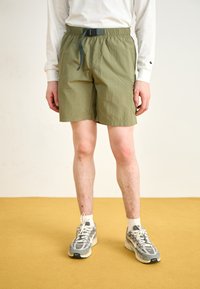 Pantalones cortos verde oliva hechos de material liviano con una cinturilla elástica y cordón ajustable, que cuentan con bolsillos laterales y una textura suave.