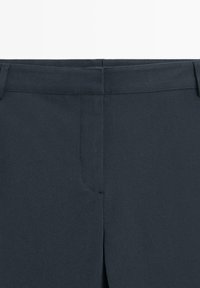 Donkergrijze op maat gemaakte broek met een soepele textuur, voorzien van zijzakken en een strakke tailleband. Geen zichtbare sluitingen of versieringen.