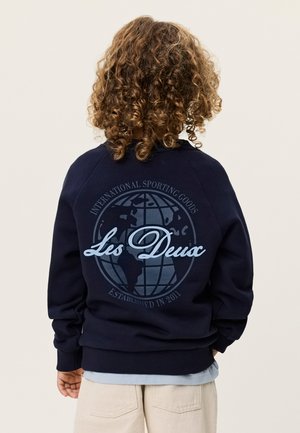 Námornícka mikina s veľkým motívom glóbusu a nápisom "Les Deux" na chrbte. Vyrobená z mäkkého materiálu s rebrovanými manžetami a lemom.