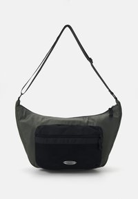 Hobo taske i mørkegrøn og sort nylon, med en afrundet form, justerbar strop, frontlomme med lynlås og en glat overflade.