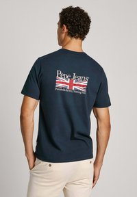 Námornícka bavlnená tričko s bielym logom "Pepe Jeans" a grafikou Union Jack na zadnej strane, s okrúhlym výstrihom a krátkymi rukávmi.