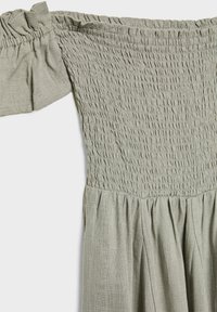 Robe vert clair à épaules dénudées avec corsage froncé élastique et manches courtes volantées, en tissu tissé texturé.