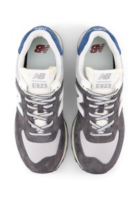 Harmaat ja valkoiset mokka- ja verkkokankaiset lenkkarit sinisillä yksityiskohdilla, joissa on nauhakiinnitys ja "574"-logo kielekkeessä, sekä teksturoitu ulkopohja.