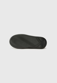 Semelle de chaussure en caoutchouc noir avec un motif en vagues, dotée d'un talon prononcé et d'une surface texturée pour une meilleure adhérence. Conçue pour la durabilité et la traction.