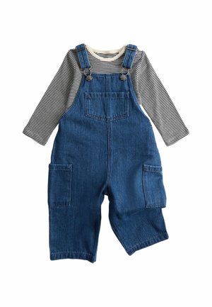 Denim-overalls med front- og sidelommer lagdelt over en langærmet sort-hvid stribet skjorte til et barn.