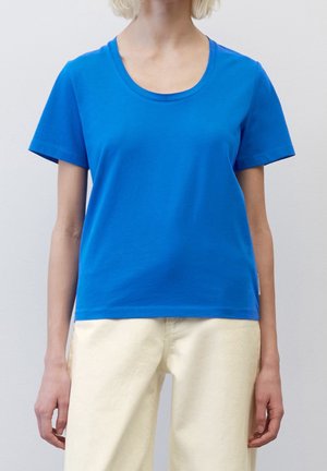Blue cotton t-shirt with a round neckline and short sleeves, paired with light yellow fabric pants. Simple design, unembellished texture.