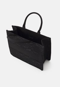Borsa a tracolla nera con una texture in pizzo, dettagli in tessuto e due manici robusti. Design aperto con un ampio interno per lo stoccaggio.