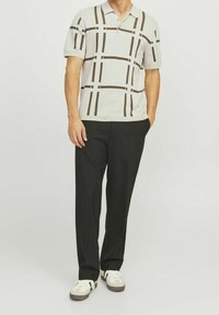 Kortärmad pikétröja i ljusgrått med mörkbrunt rutmönster, kombinerad med svarta byxor och vita sneakers, med en klassisk krage.