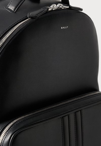 Sac à dos en cuir noir Bally avec fermetures éclair argentées et poche avant, montrant le matériau texturé et le logo de la marque sur la partie supérieure.