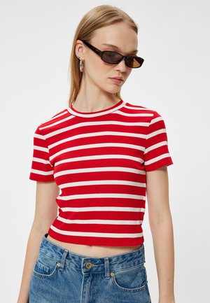 Rød og hvid stribet kortærmet crop top, ribbet struktur, rund halsudskæring, kombineret med blå højtaljede jeans og mørke solbriller.