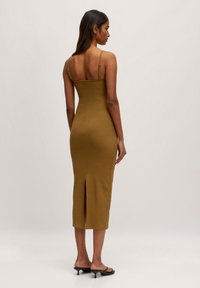 Olivengrünes Midikleid mit dünnen Trägern, taillierter Passform und Schlitz hinten. Glatte Textur, knielang und minimalistischer Stil.