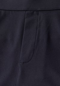 Tmavě modrá tkanina s hladkým povrchem, viditelným švem podél okrajů a boční kapsou integrovanou do designu.