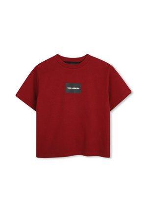 T-shirt rouge court avec manches courtes et petit patch logo rectangulaire noir portant la mention "Karl Lagerfeld" centré sur la poitrine.