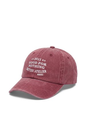 Versleten rode baseballpet met witte tekst ""2011 Good For Nothing British Atelier MMXI"" op het voorpaneel.