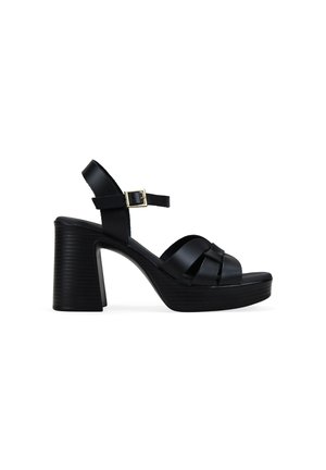 Sandalia de plataforma de cuero negro con tacón alto grueso, puntera abierta, diseño de tira tejida y hebilla de tobillo ajustable.