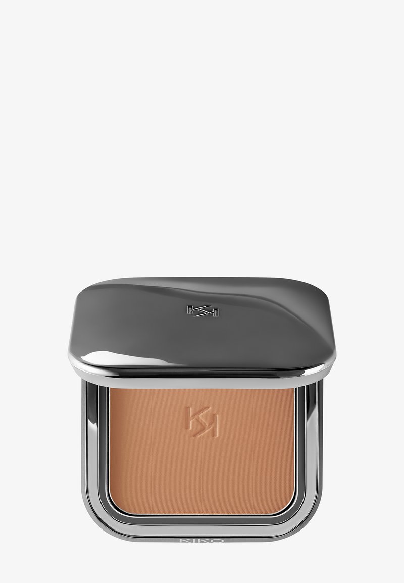Kompaktpuder med ett slankt, reflekterande silveretui. Försiktig ljusbrun puder med ett präglat logotyp. Rundade kanter.