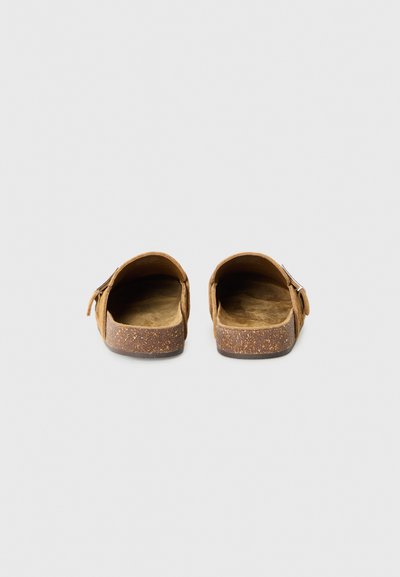 Bruna slip-on sandaler med platt korksula, övre del i mockaliknande material, och justerbart remmar. Mjuk innersula för komfort.