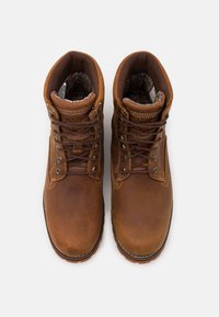 Bottines en cuir marron avec bouts ronds, œillets en métal et lacets marron. L'intérieur présente une doublure à motifs. Semelles en caoutchouc pour une meilleure adhérence.
