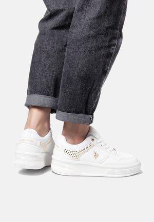 White sneakers made of synthetic material with perforated accents and gold branding. Rounded toe, lace-up design, and thick sole.