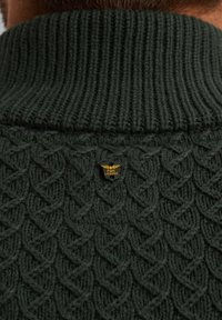 Dunkelgrüner Strickpullover mit einem gerippten hohen Kragen und einem gemusterten, strukturierten Körper. Verfügt über ein kleines goldenes Emblem auf der Rückseite.