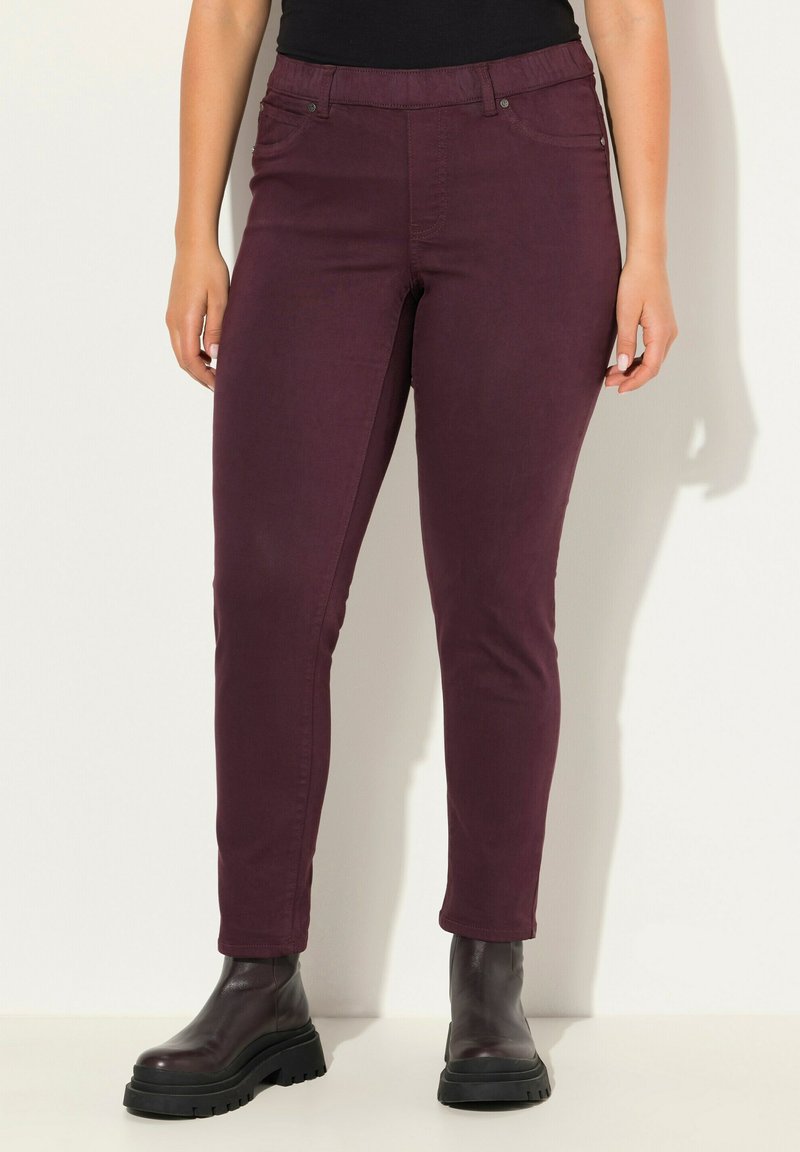 Burgundské slim-fit džíny s pěti kapsami, se zipem a knoflíkovým zapínáním. V kombinaci s černými silnými botami na podpatku.