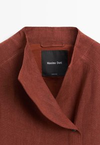 Linnen blazer in roestkleur met notched reverskraag en zwart binnenlabel met de tekst "Massimo Dutti," gemaakt in China.