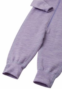 Fioletowy kombinezon na zamek, wykonany z miękkiego, teksturowanego materiału. Posiada długie rękawy z ściągaczami oraz kontrastowe przeszycia wzdłuż szwów.