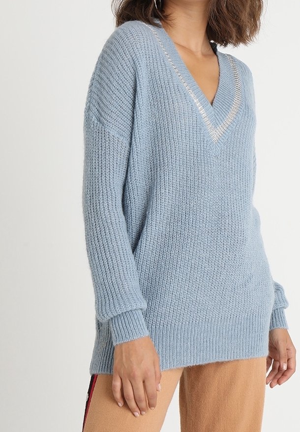 Ljusblå stickad tröja med V-hals och silverdetaljer, med en avslappnad passform samt ribbade manschetter och nederkant. Strukturerad tyg synlig.