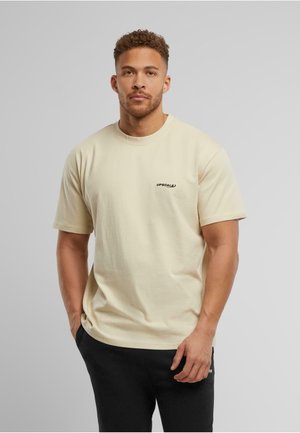 Casual cream cotton t-shirt with short sleeves and a round neck. Features a small black "UPGRADE" logo on the left chest.