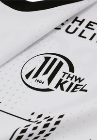 Weißer Sporttrikotstoff mit dem THW Kiel-Logo in Schwarz, versehen mit geometrischen Mustern und der aufgedruckten Jahreszahl 1904.