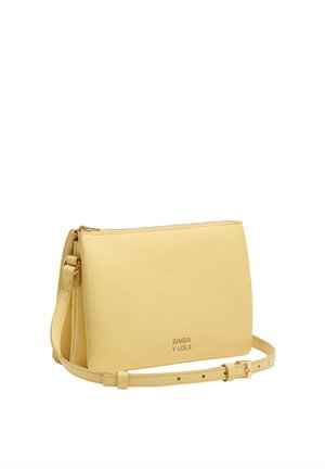 Bolso bandolera rectangular de color amarillo pálido con correa ajustable, hebilla dorada, cierre de cremallera y logo "BIMBA Y LOLA" en la parte frontal.