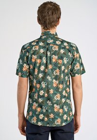 Camicetta a maniche corte in tessuto verde scuro con un motivo floreale che presenta fiori arancioni, crema e verde acqua, oltre a foglie di palma.