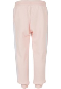 Gaiši rozā sporta bikses ar mīkstu tekstūru, kurām ir baltas sānu svītras, elastīgs jostasvīrs un piedurknes apakšā. Vienkāršs, pielāgots dizains.