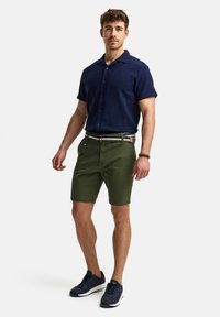 Marine blauw korte mouwen overhemd, groene shorts en marineblauwe sneakers. Geaccentueerd met een multi-gestreepte riem en een gestructureerde stof.