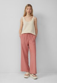 Beige gebreide tanktop met een ronde hals, gecombineerd met brede, lichtroze broeken met een elastische taille en zijzakken.