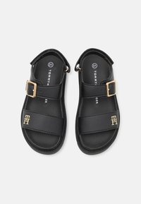 Sorte lær sandaler med to brede stropper, justerbar gullspenne og logo detaljer. Har en glatt overflate og åpen bakdesign.