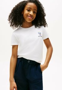 Hvid bomulds t-shirt med korte ærmer, der har et popcorn grafik og "Tommy Hilfiger" tekst, parret med marineblå bukser med elastisk talje.