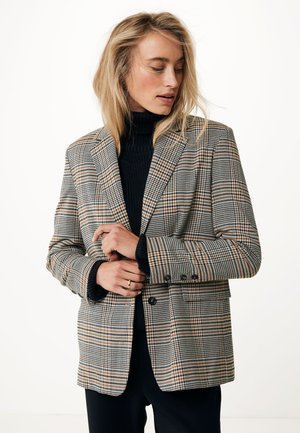 Plaid blazer in shades of brown, black, and cream, featuring structured shoulders, double-button front, and side pockets. Textured fabric.