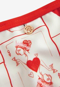 Červeno-biela látka so hravými ilustráciami ženských postáv a sŕdc. Obsahuje kruhový zlatý logotyp ako ozdobu.