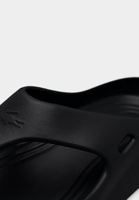 Schwarze Gummi-Sandale mit glatter Textur, ausgestattet mit einem breiten Riemen und einem Ausschnitt-Design. Deutlich sichtbares Logo-Detail an der Seite.